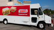 A delivery truck displaying the Bimbo Bakeries logo and photos of sandwiches made on white bread. 