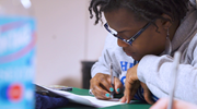 Close-up of an educator filling out paperwork at a desk during a training session.