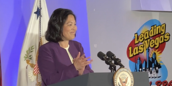 Acting Secretary Su smiles at a podium. Behind her a sign reads "Leading Las Vegas"