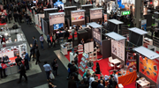 View from above of people and booths in a large room at an exhibition of information technology.