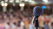 A microphone stands in front of a blurred background