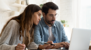 A man and woman look at a laptop screen.