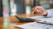 A person taps on a calculator while reviewing financial statements.