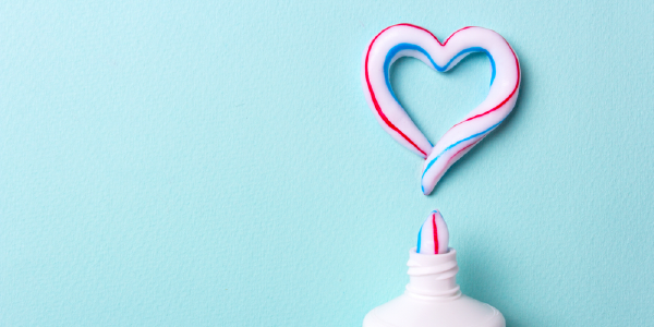 Toothpaste shaped like a heart on a blue background.