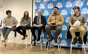 Several people sit on tall chairs as part of a panel with a Restaurant Opportunities United banner behind them.