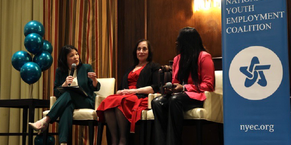 Acting Secretary Su speaks on a three-woman panel. A banner on the stage reads National Youth Employment Coalition.