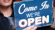 A worker hangs a âCome in, weâre openâ sign on the door of a business. 