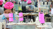 A garment worker at a Better Work factory in Vietnam. Spools of pink thread are visible in the foreground. Credit: Better Work. 