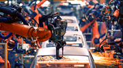 A car production line. Large, arm-line machines weld pieces of the auto body together, causing sparks to fly.