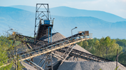 A sand or gravel mine with piles of rocks and several large conveyors. 