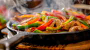 Steaming fajitas with shrimp, peppers and onions served in a cast iron skillet.