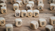 Small alphabet blocks are scattered across a table. In the center, four blocks spell out the word help.