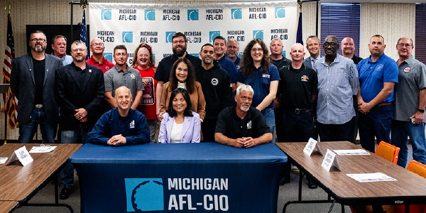 Dozens of people gather for a group photo in front of signs reading âMichigan AFL-CIOâ