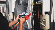 Person using a manifold gauge set to check air conditioning system pressures.