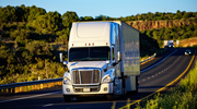 Seen from the front, a white semi-truck drives on a highway in Arizona. 