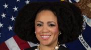 Professional head shot of Taryn Williams, head of ODEP, shows a Black woman smiling in front of American and Labor Department flags.