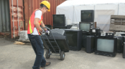 Worker with an old TV on a rolling hand truck.