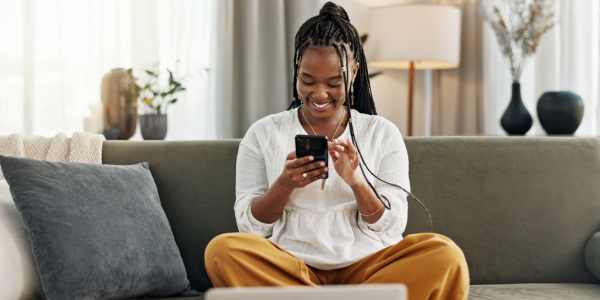 Happy Black woman smiling as she looks at her phone.