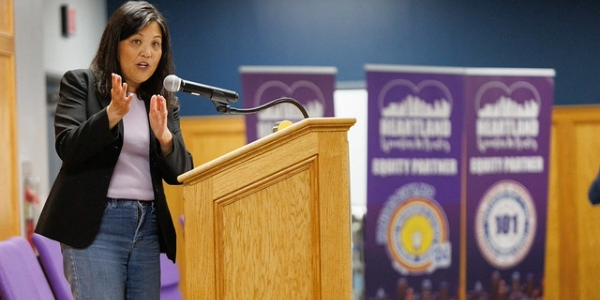 Acting Secretary Su speaks behind a dias while wearing a blazer