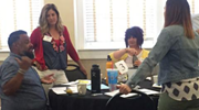 Several people engage in discussion around a table.