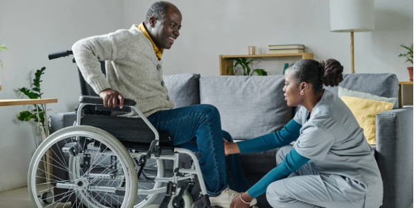 A care worker helps an older person in a wheelchair