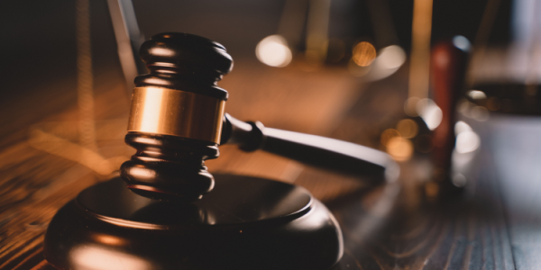 A wooden gavel on a round block atop a table.