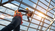 Construction workers install new roof wearing fall protection devices. 