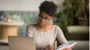 A young woman looks at her computer while evaluating her finances.