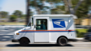 Blurred image of USPS mail truck in motion.