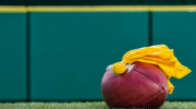 Yellow penalty flag atop football on grass