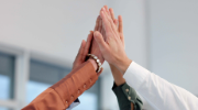 A group of hands raised up in a high-five in an office setting.