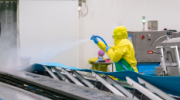 Worker used high pressure water spray cleaning conveyor belt in chicken meat process.