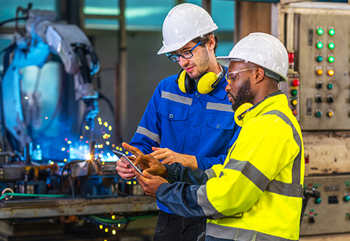 Engineers working on a tablet dressed with hardhats.
