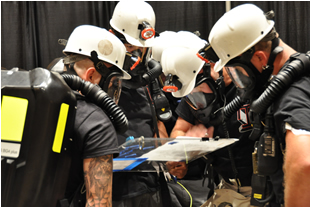Rescue teams study mine map to locate trapped miners in simulated emergency drill.