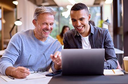 Two people looking at a computer screen and smiling.