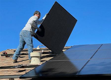 Person installing solar panels on a roof